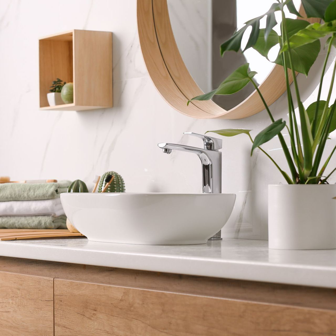 Un évier avec une plante et un miroir circulaire