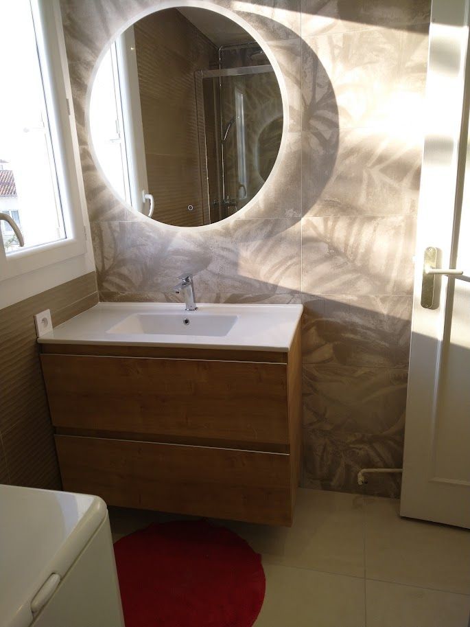 Une salle de bains avec un évier et un miroir circulaire