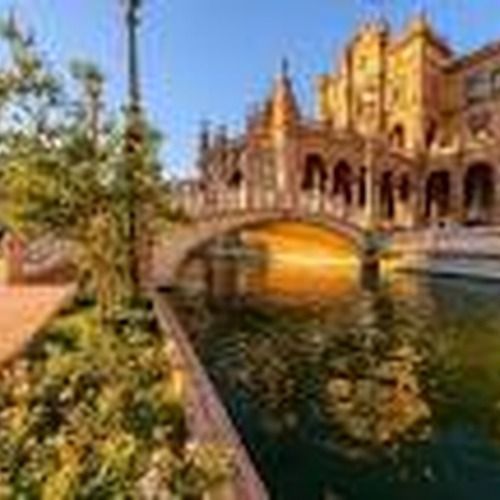 Puente sobre el agua con edificio adornado en el fondo.