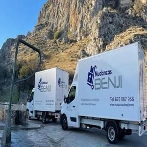 Dos camiones de mudanzas Benji blancos en la montaña aparcados.
