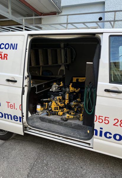 Weisser Lieferwagen mit offener Seitentür, an der gelbe Elektrowerkzeuge zu sehen sind.