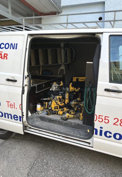 Weisse Toilette neben einer Glasdusche in einem Badezimmer. Weisse Fliesen mit schwarzem Rand. Handtuchhalter.