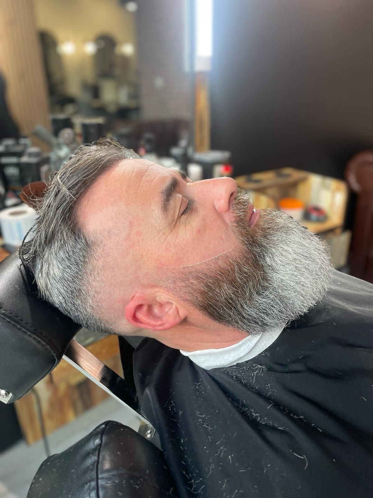 Un hombre con barba se está cortando el pelo en una barbería.