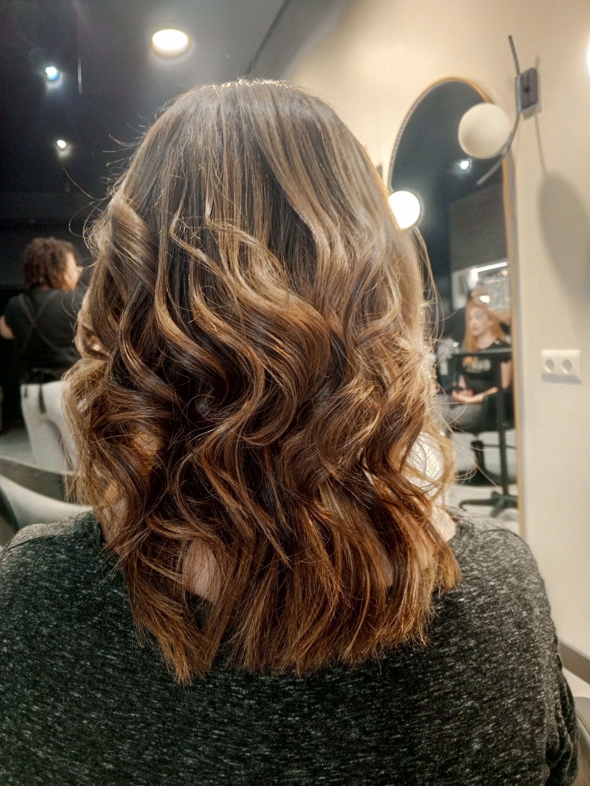 Una mujer con cabello rizado está sentada en una silla en un salón.