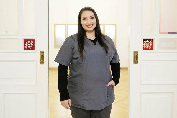 Eine Frau im OP-Kittel steht vor einer Tür.