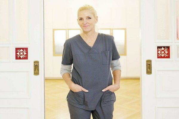 Eine Frau im OP-Kittel steht vor einer Tür