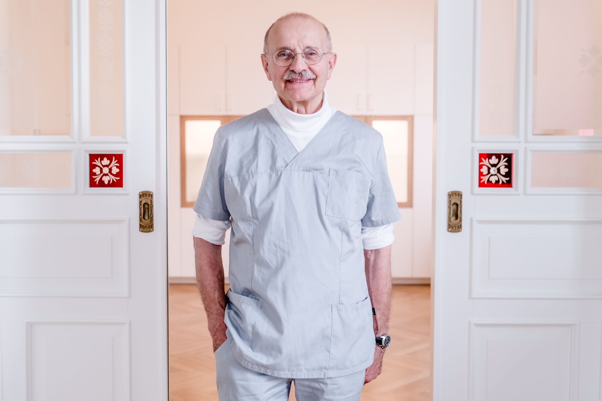 Ein Mann im OP-Kittel steht vor einer Tür.