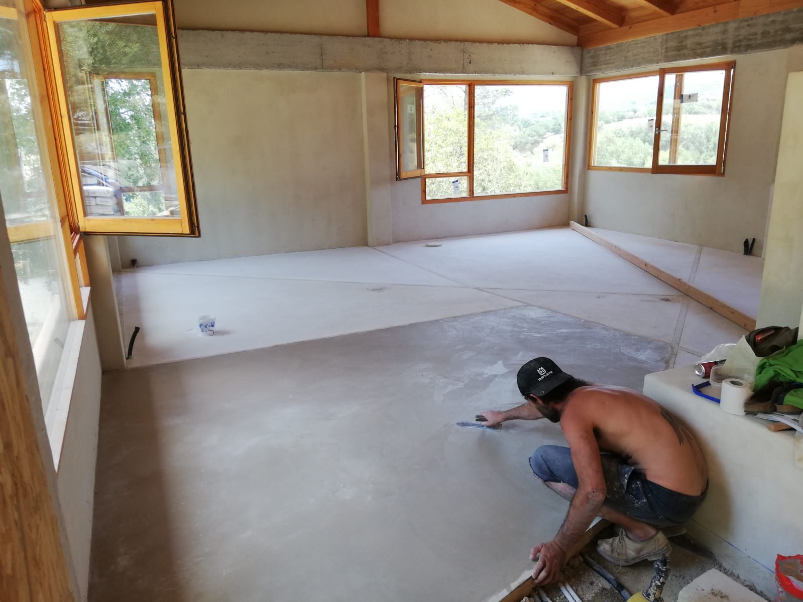 Un hombre está arrodillado en el suelo en una habitación con muchas ventanas.