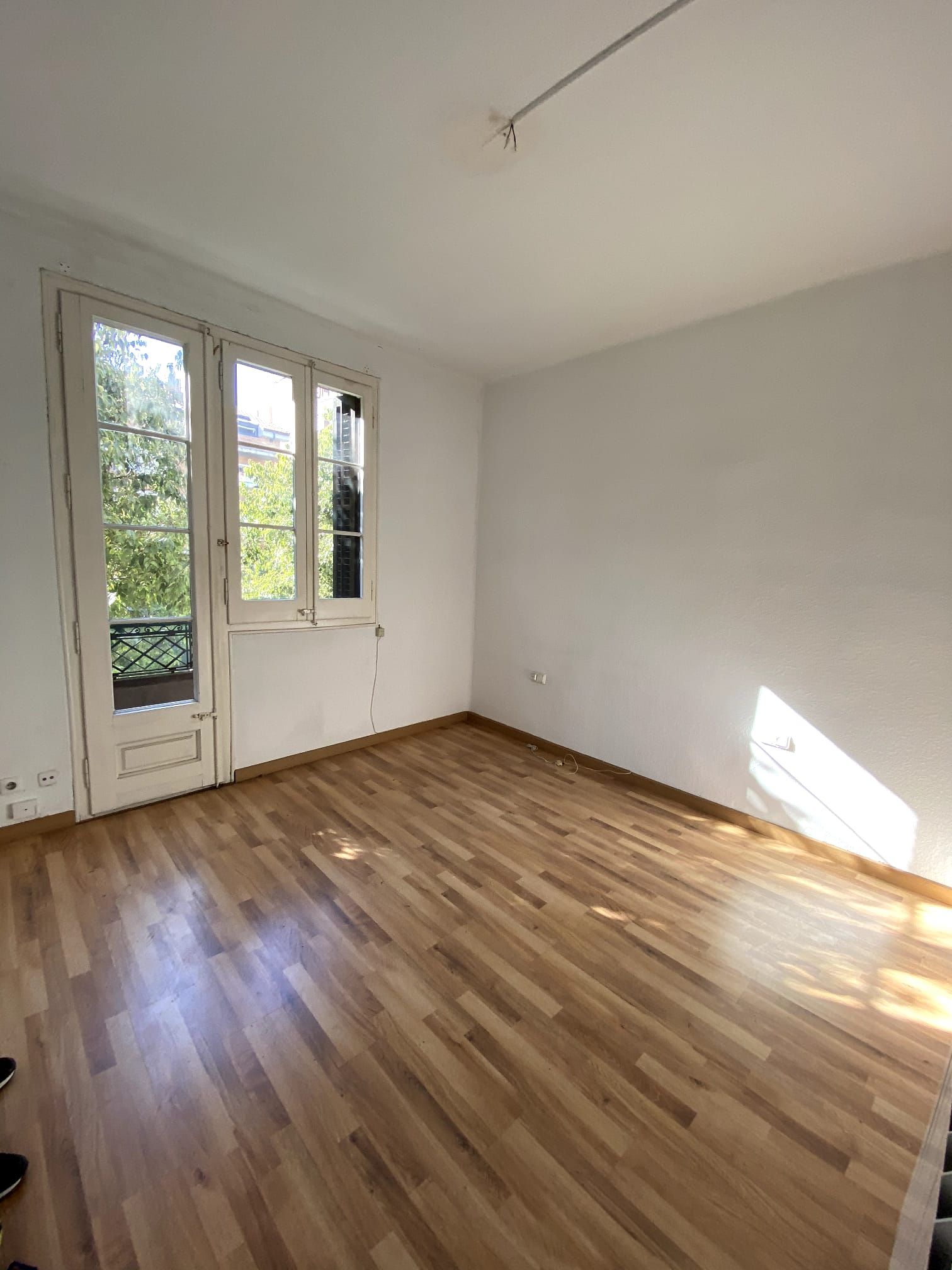 Una habitación vacía con pisos de madera y dos ventanas.