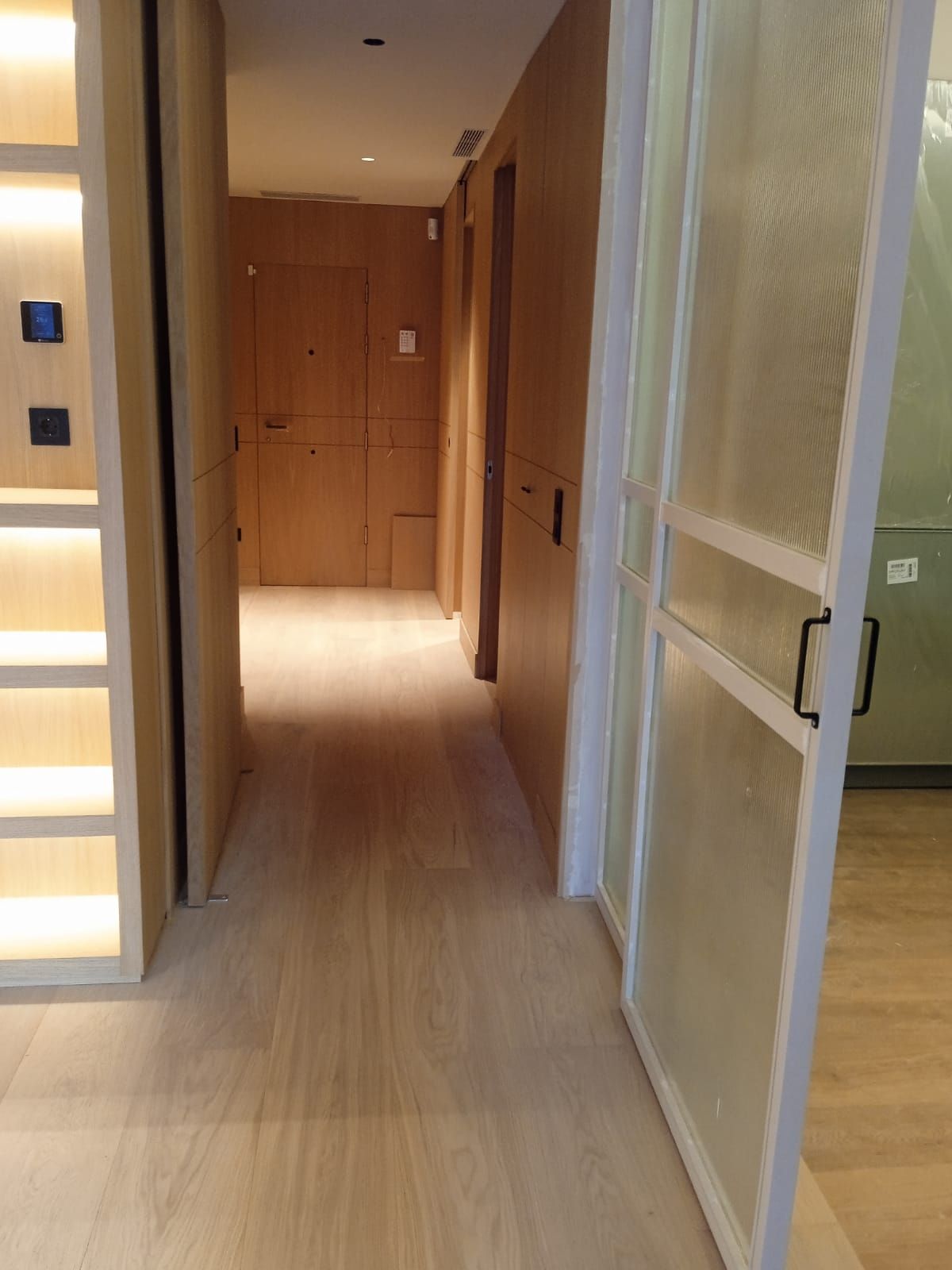 Un pasillo con una puerta de cristal y paredes de madera.