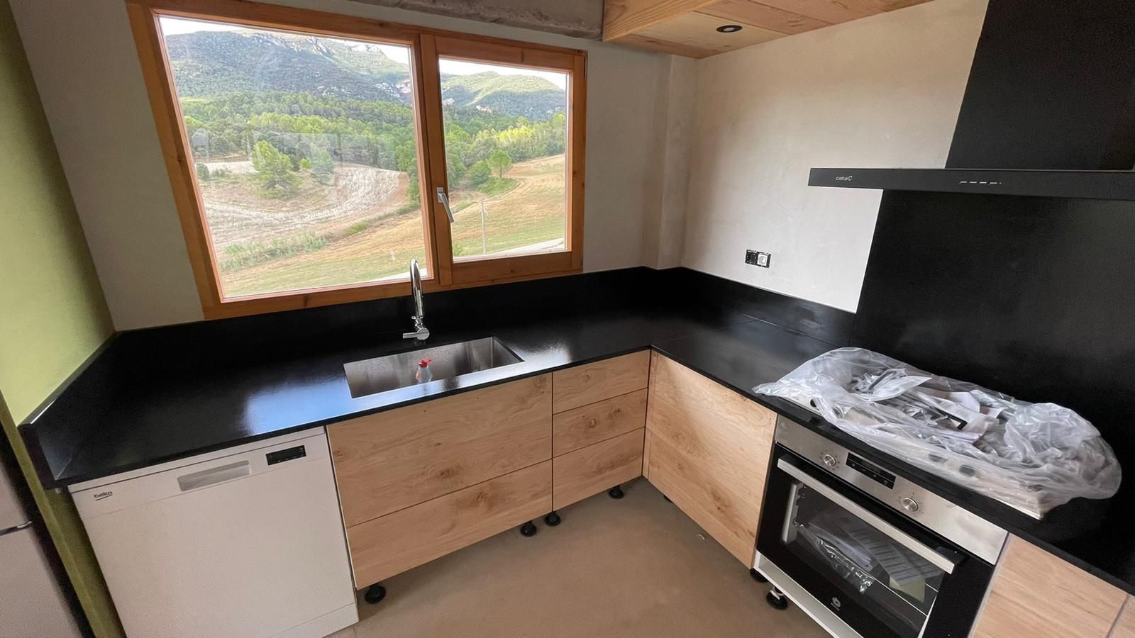 Una cocina con fregadero, estufa, lavavajillas y ventana.