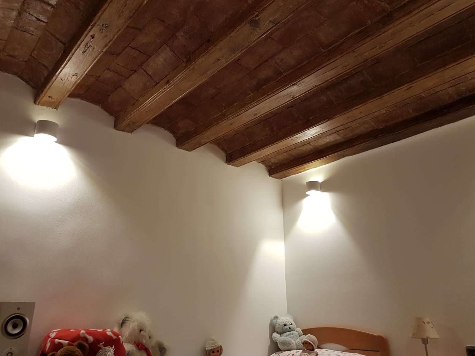 Un dormitorio con techo de madera y una cama con animales de peluche encima.