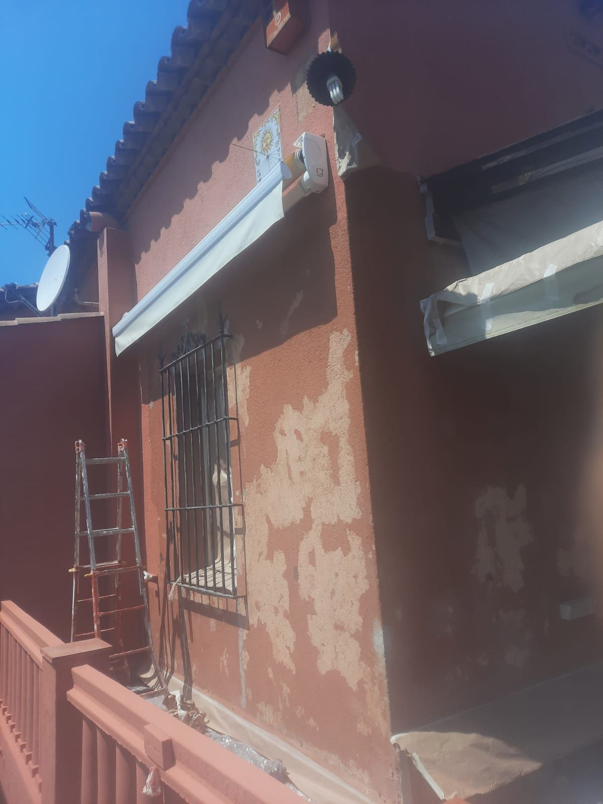 Un edificio rojo con un toldo blanco al costado.