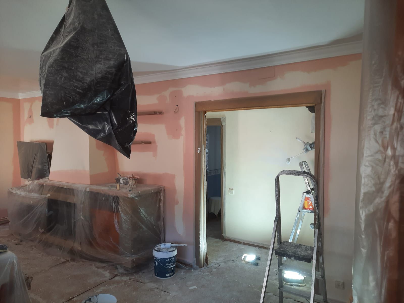 Una habitación con una escalera y cubos de pintura dentro.