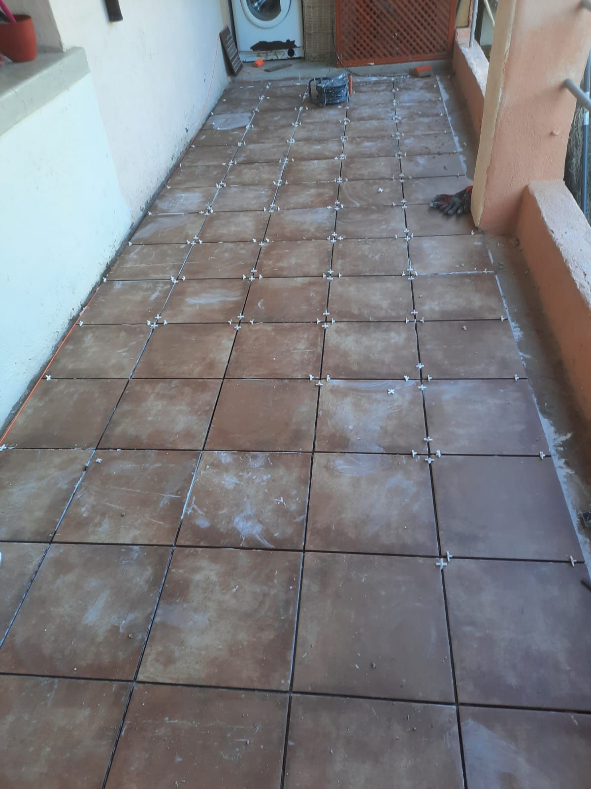 Se está instalando un suelo de baldosas en un balcón.