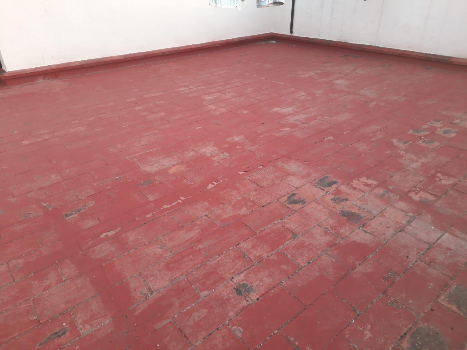 Un suelo de baldosas rojas con una pared blanca al fondo.