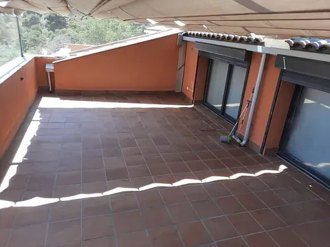 Una terraza en la azotea con suelo de baldosas y puertas corredizas de vidrio.