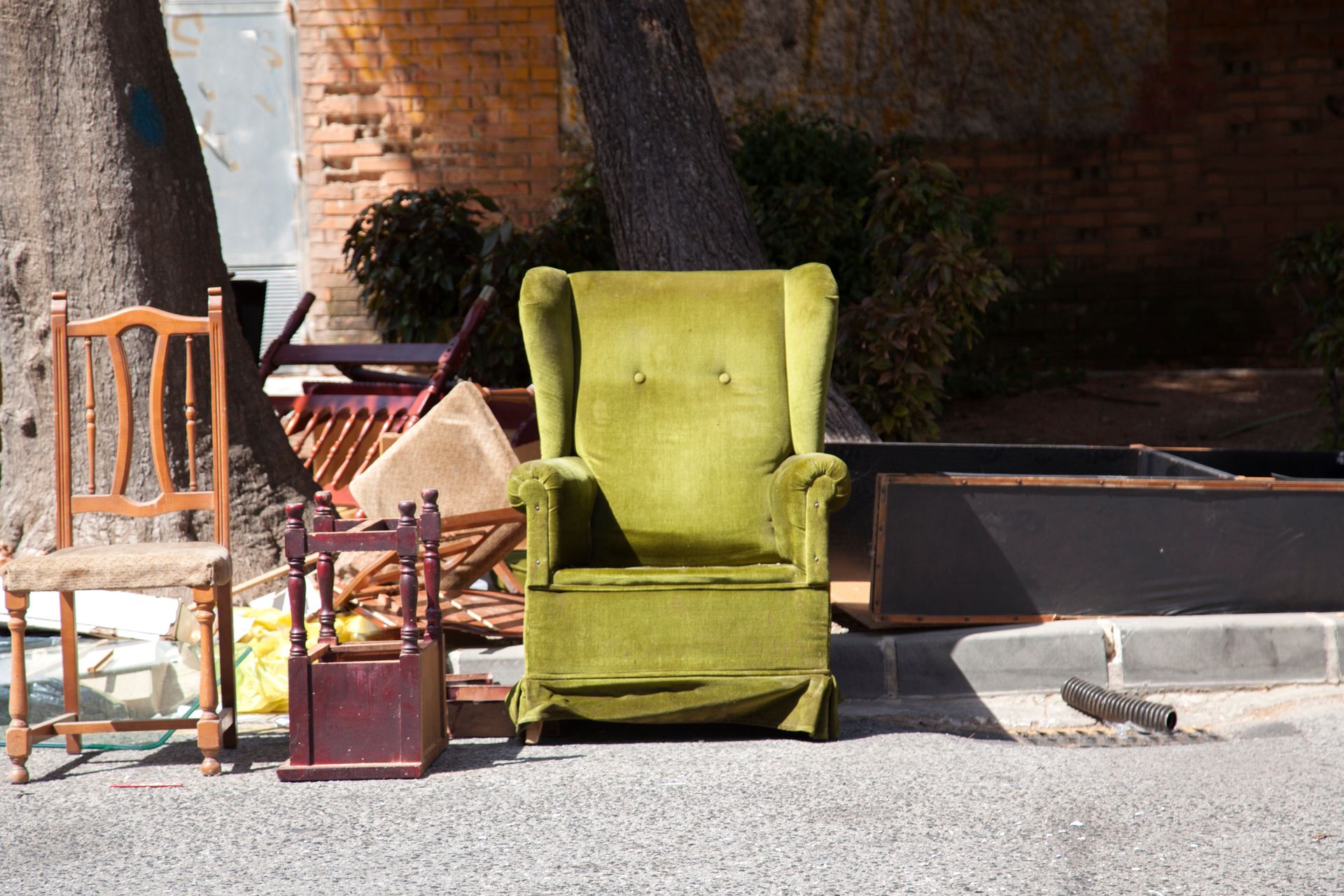 Fauteuil vert et chaise en bois sur un trottoir ensoleillé, près d'un mur de briques