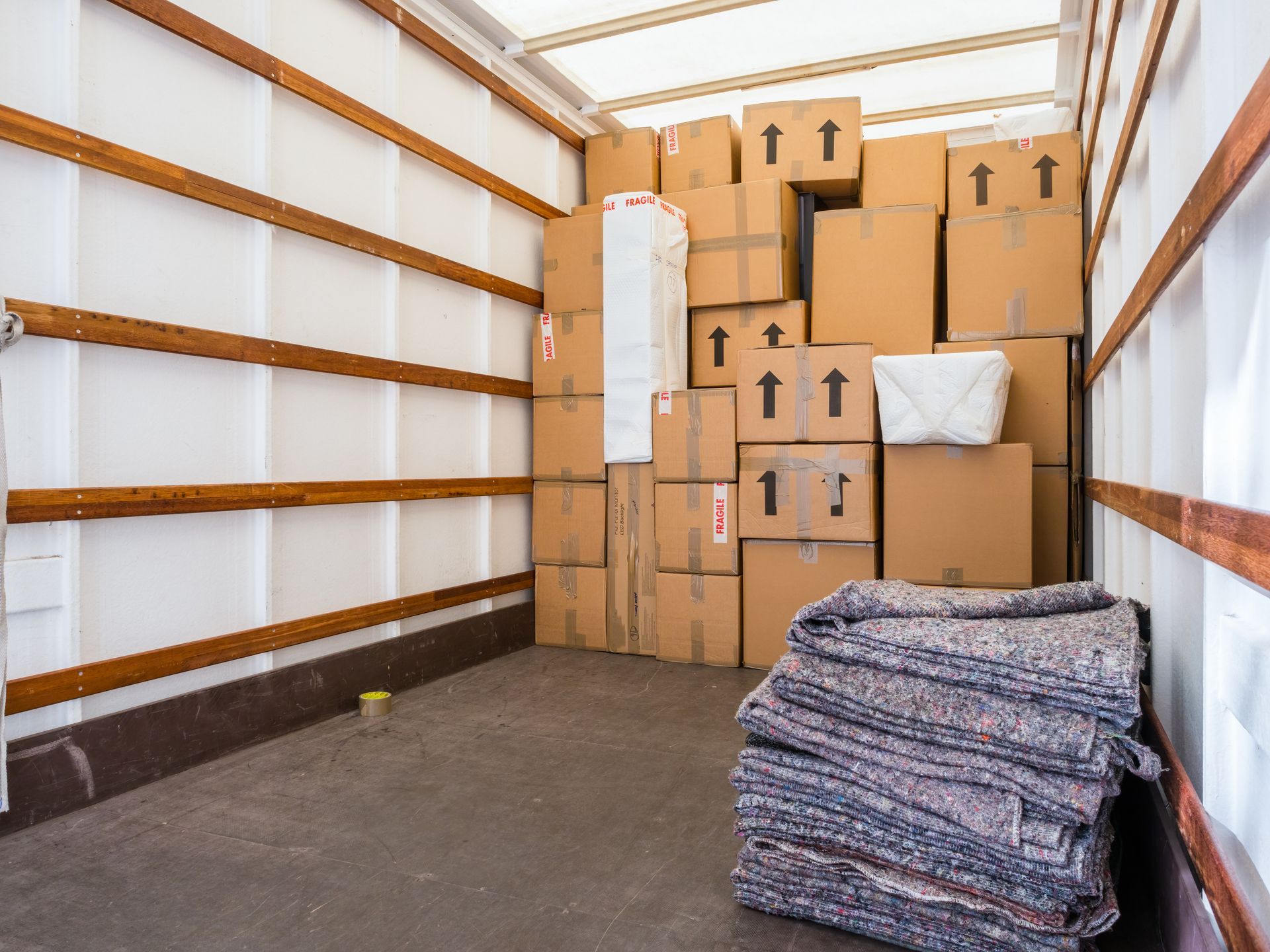 Camion de déménagement avec des cartons empilés et des couvertures pliées à l'intérieur.