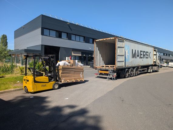 Un chariot élévateur décharge des palettes d'un camion à côté d'un bâtiment industriel moderne