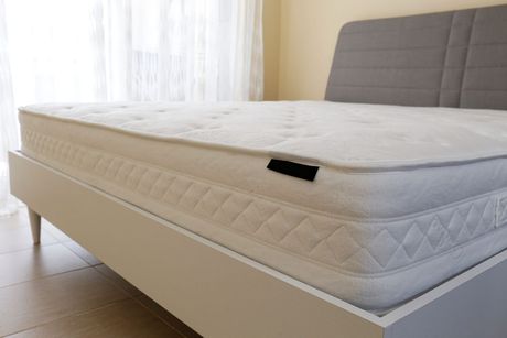 Sofá cama extraíble, cubierto de plástico. Se ven secciones beige del sofá.