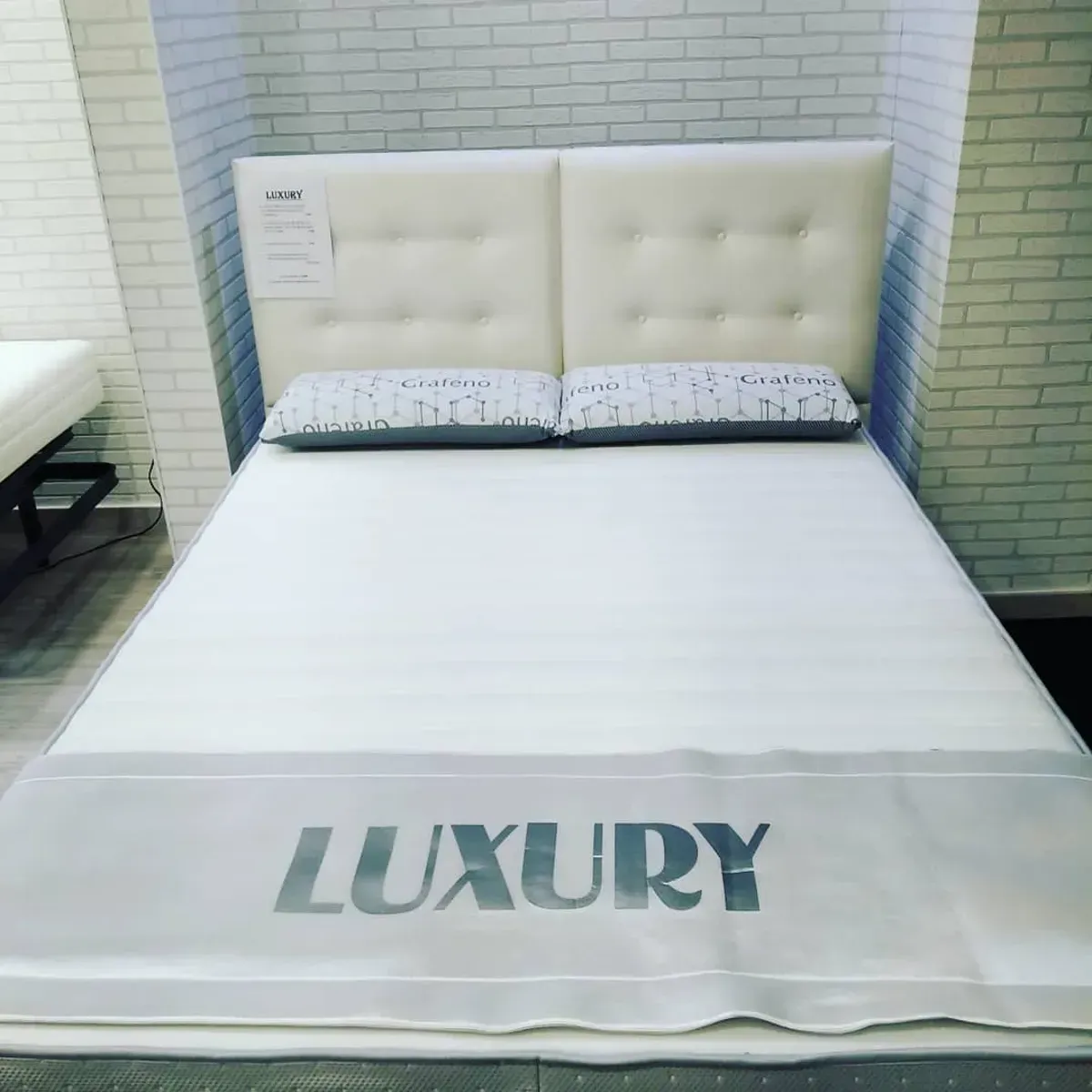 Una cama blanca con cabecero capitoné con la palabra