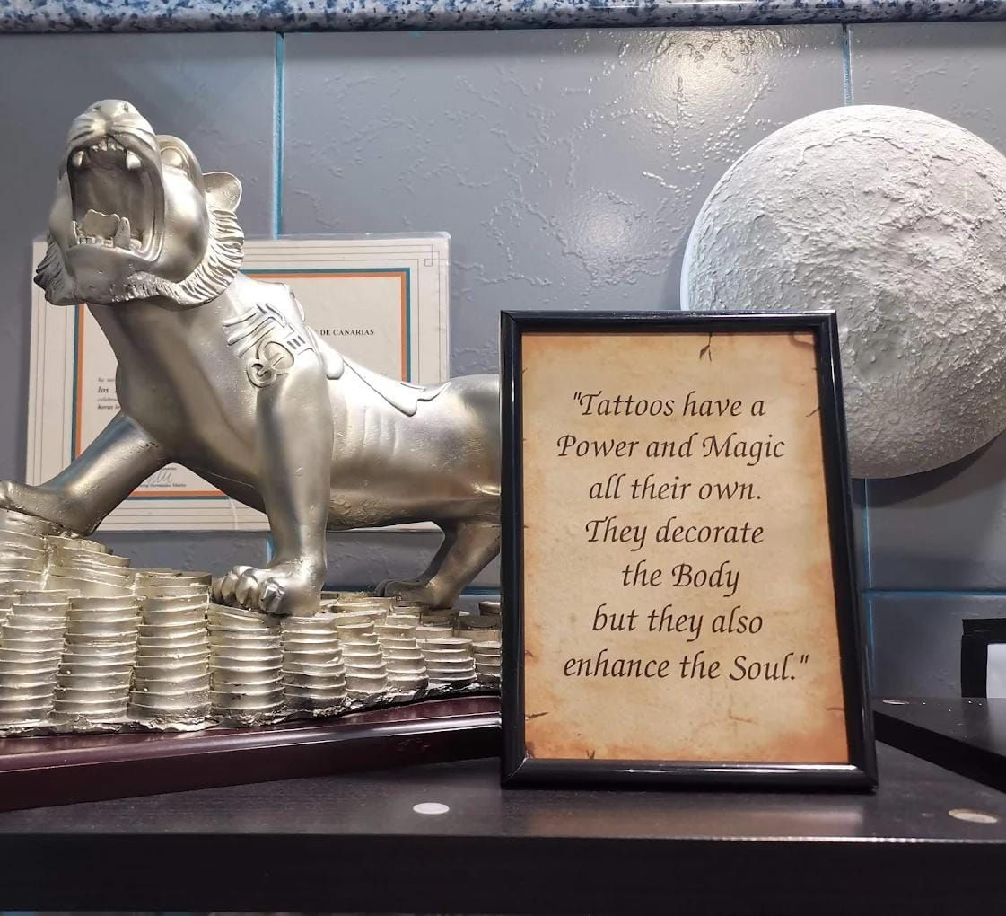 Estatua de león de plata con la cita enmarcada: «Magia y Poder». Al fondo, una escultura de luna.