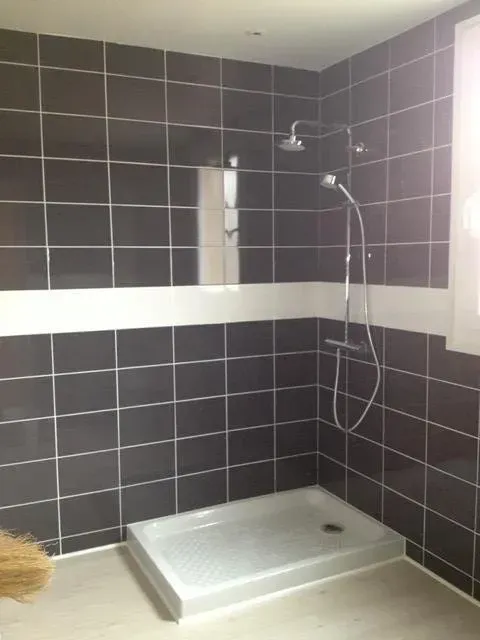 Une douche avec carrelage noir et faïence blanche