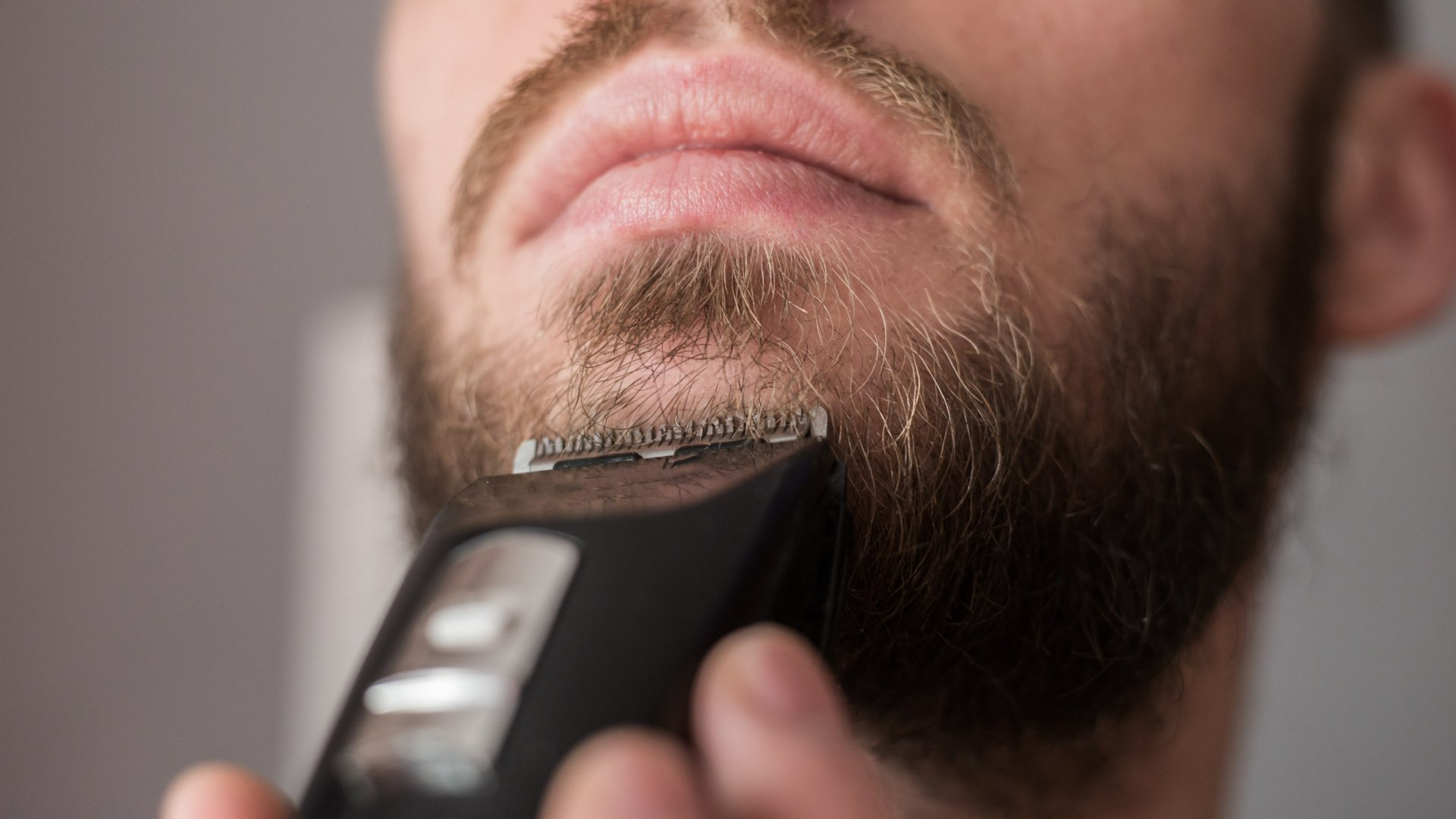 Homme se taillant la barbe avec une tondeuse