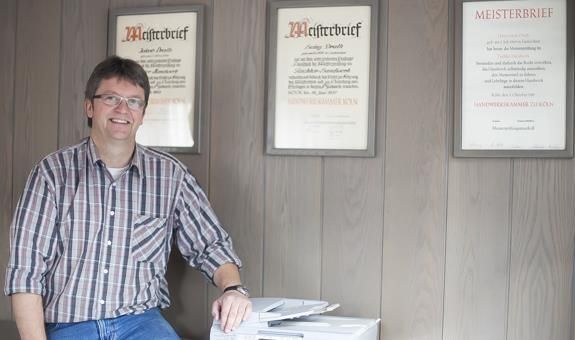 Ein Mann im karierten Hemd sitzt vor einem Drucker