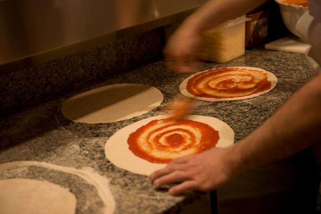 Application de la base tomate sur une pâte à pizza