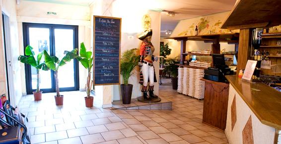 Intérieur du restaurant le Novello dans lequel se trouve une ardoise, des plantes vertes et une grande statue décorative