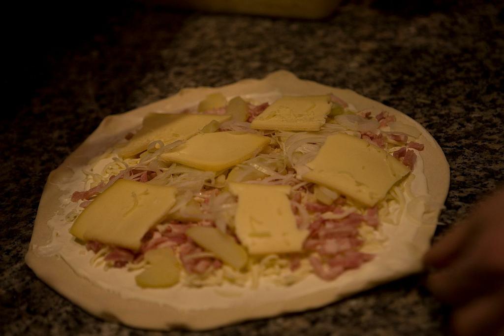 Pizza aux lardons, pommes de terre, oignon et fromage juste avant de passer au four