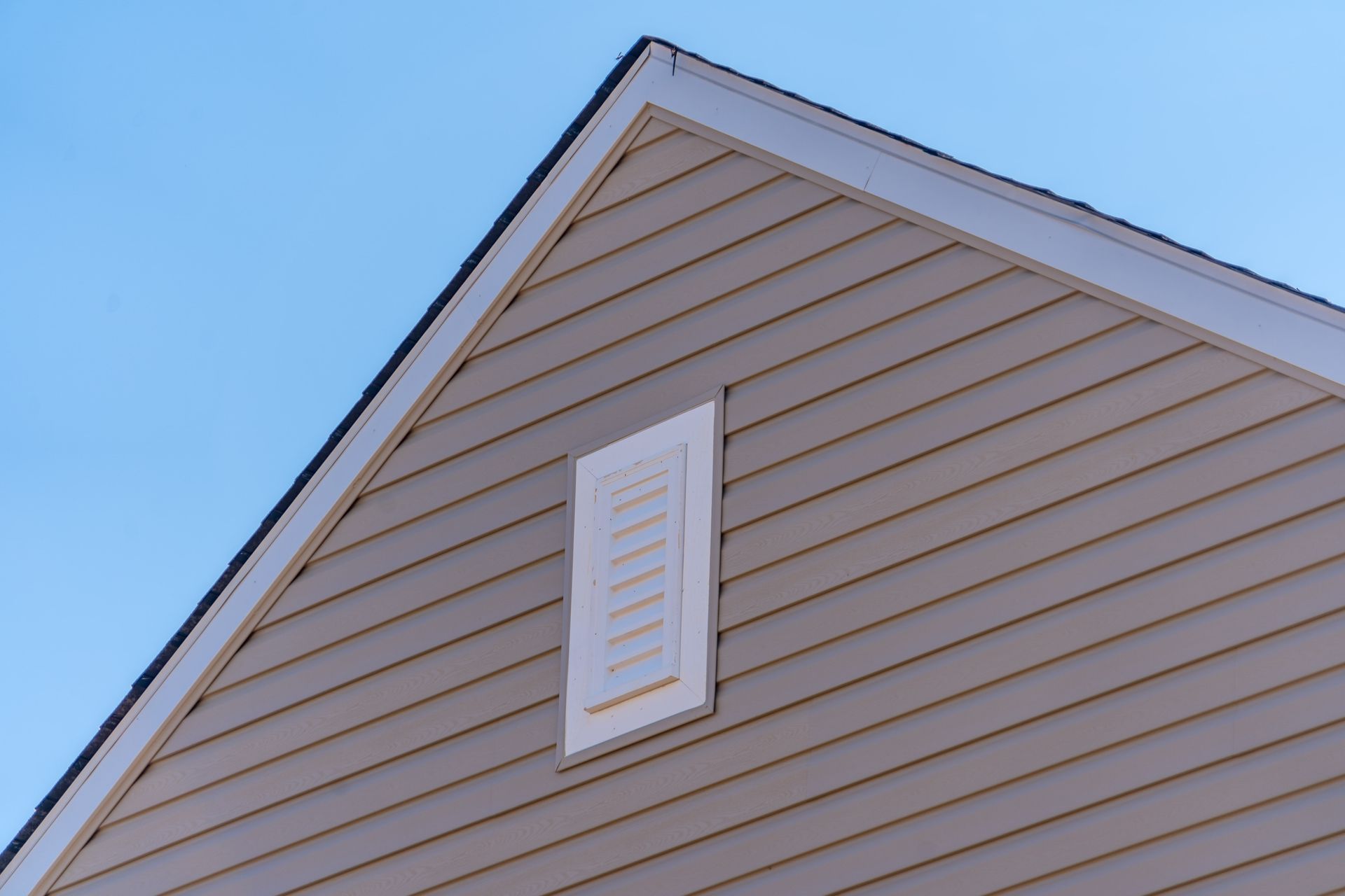 Bardage en PVC de couleur beige sur une façade de maison.