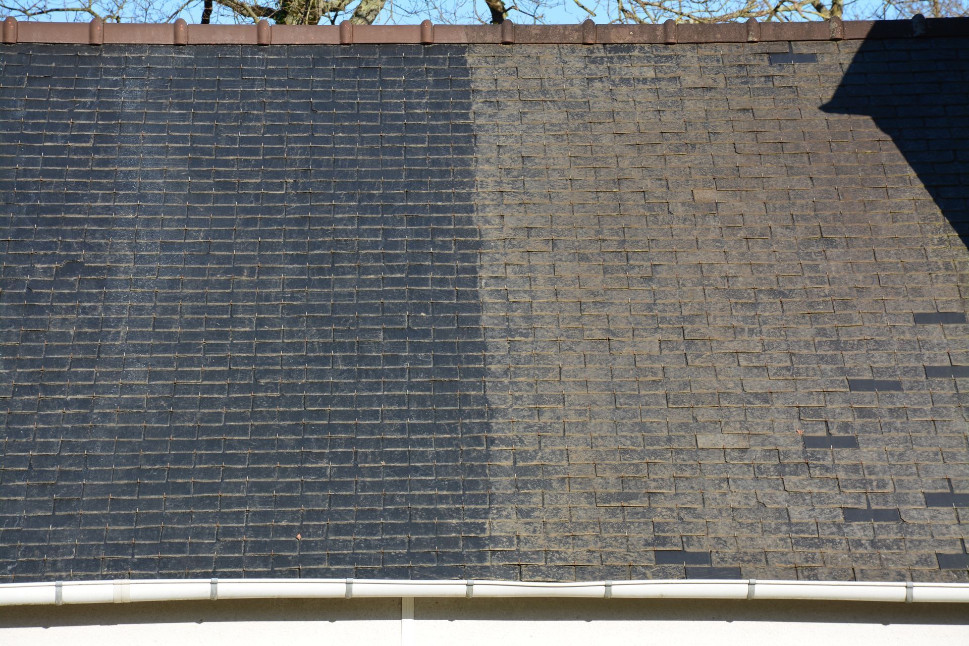 Toiture en ardoise en partie nettoyée.