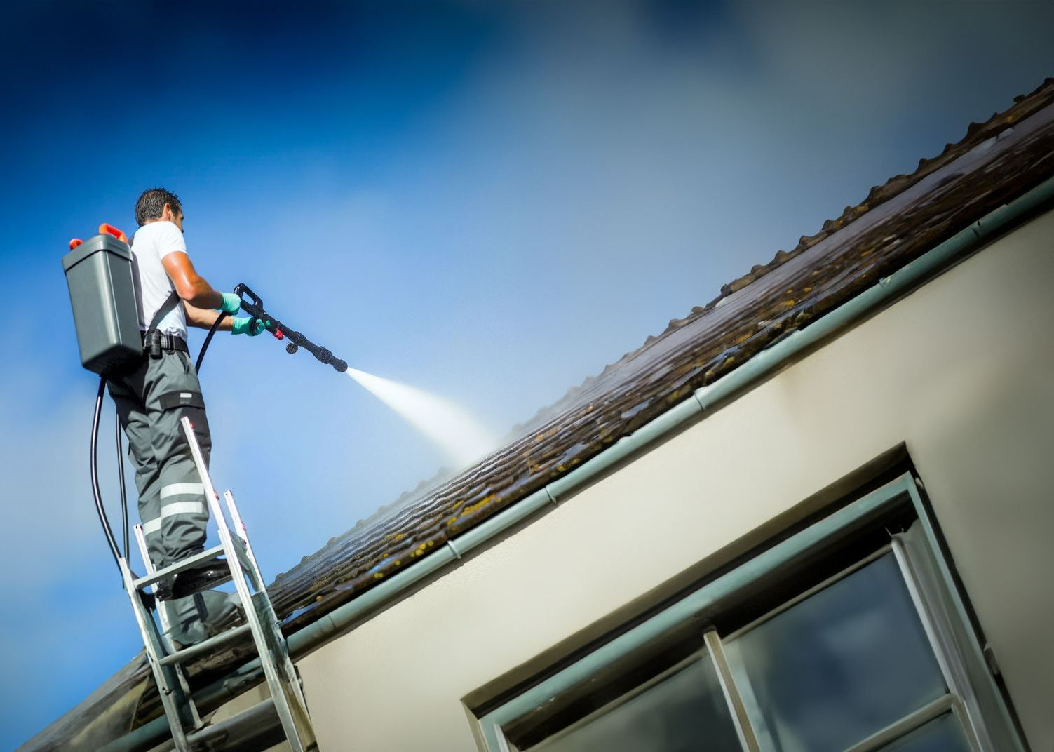 Couvreur appliquant un traitement hydrofuge sur une toiture.