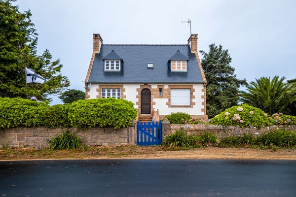 Maison à la façade en granit recouverte d'un crépi blanc.