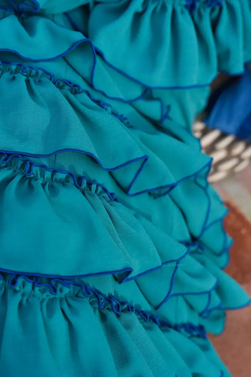 Tela verde azulado con múltiples capas con volantes, cada una bordeada con costuras azul oscuro.