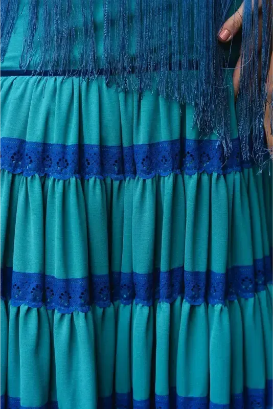 Falda verde azulado con ribete de encaje azul y parte superior verde azulado con flecos.