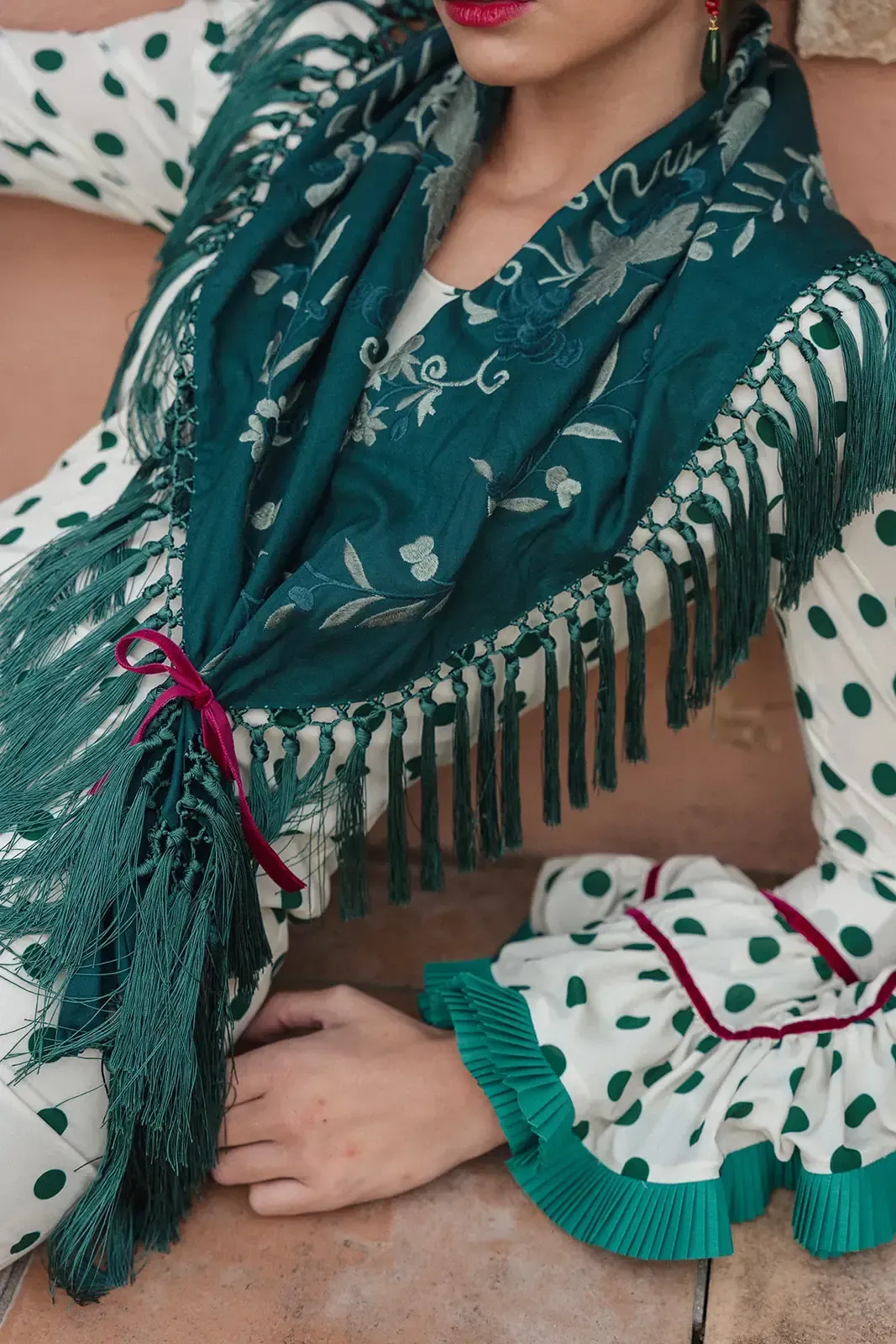 Mujer con vestido de lunares con chal verde y flecos, cinta burdeos.