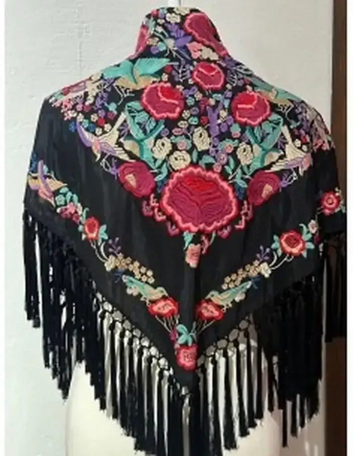 Chal cuadrado negro con bordado floral vibrante y flecos largos.