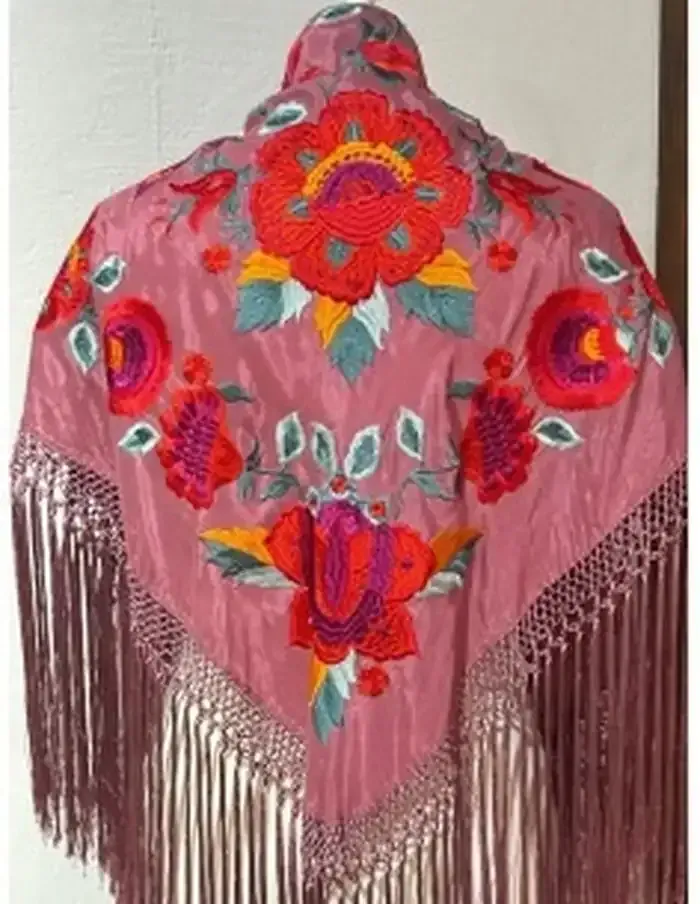 Chal bordado de color rosa con grandes diseños florales coloridos y flecos.