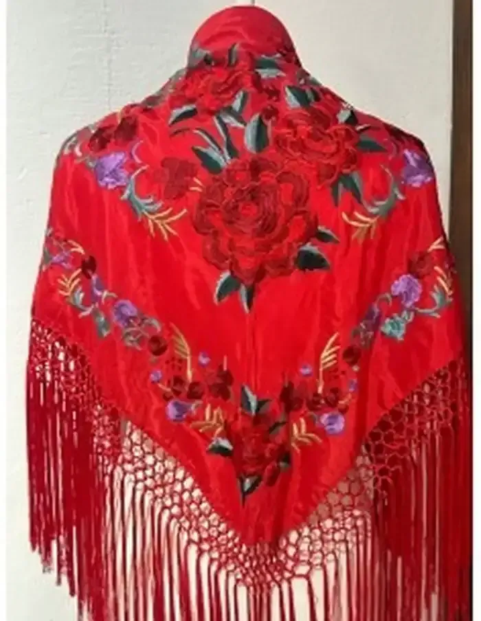 Chal rojo bordado con flecos largos, colocado sobre un maniquí.