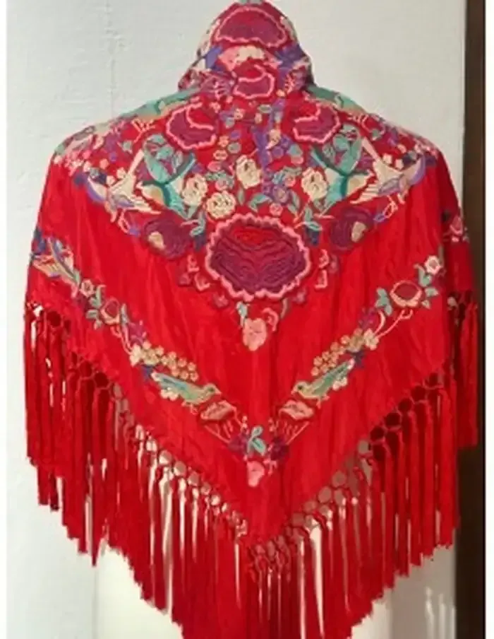 Chal rojo con intrincado bordado floral y flecos largos.