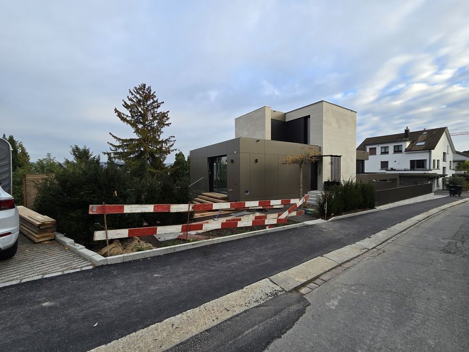Ein Auto steht vor einem Haus, das gerade gebaut wird. Foto von der RRB GmbH