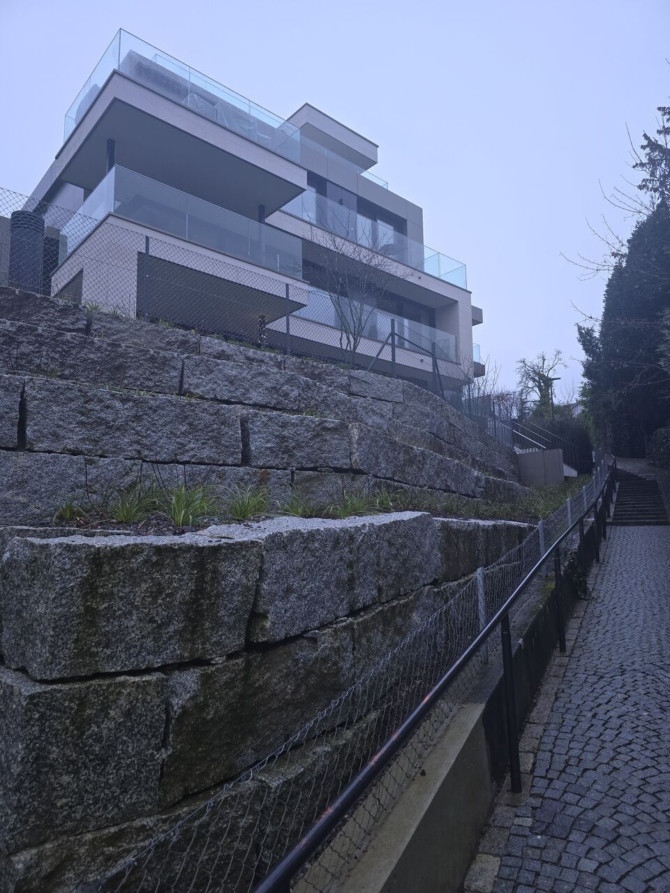 Ein grosses Gebäude steht auf einem Hügel neben einem Kopfsteinpflasterweg. Foto von der RRB GmbH