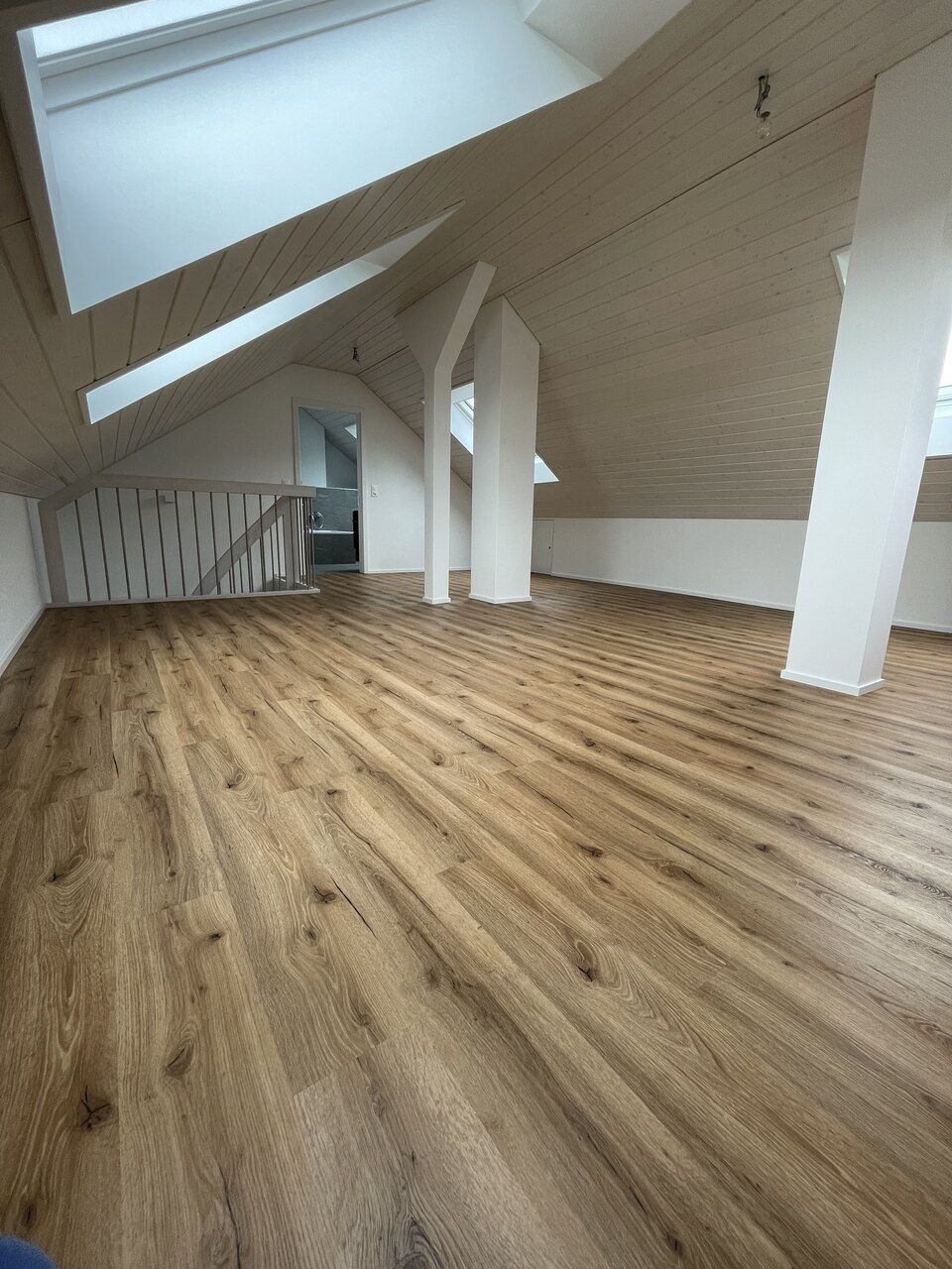 Ein leerer Dachboden mit Holzboden und weissen Wänden. Foto von der RRB GmbH