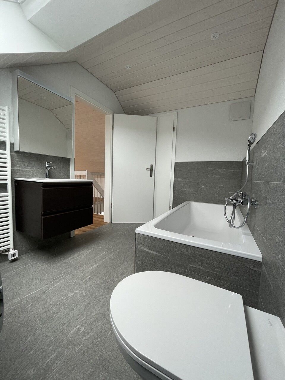 Ein Badezimmer mit Badewanne, Toilette, Waschbecken und Spiegel. Foto von der RRB GmbH