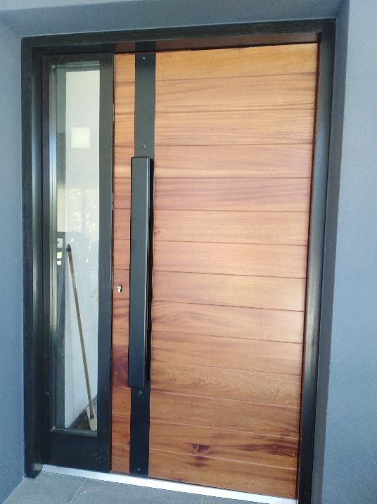 Porte d'entrée en bois sur une ossature métallique