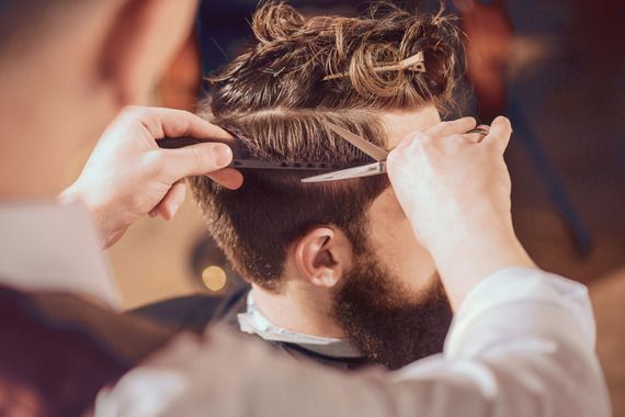 Ein Friseur schneidet einem Kunden in einem Salon mit einer Haarschneidemaschine die Haare.